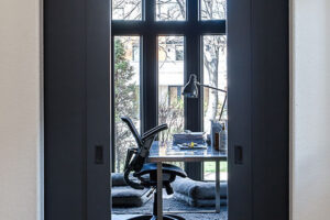 hallway view of sliding gray doors leading into minimalist office JM Kitchen & Bath Design