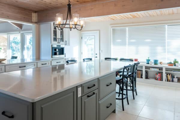 large kitchen remodel features large island, bar, and extra storage shelving along large window JM Kitchen & Bath Design