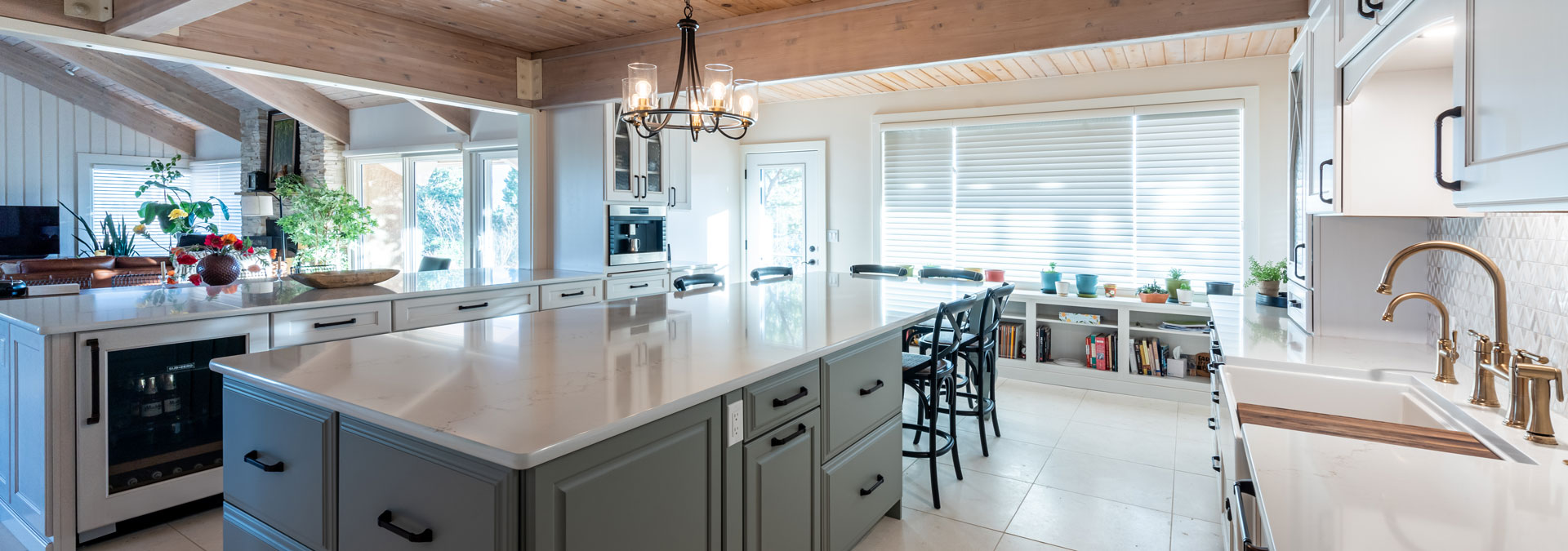 large kitchen remodel features large island, bar, and extra storage shelving along large window JM Kitchen & Bath Design