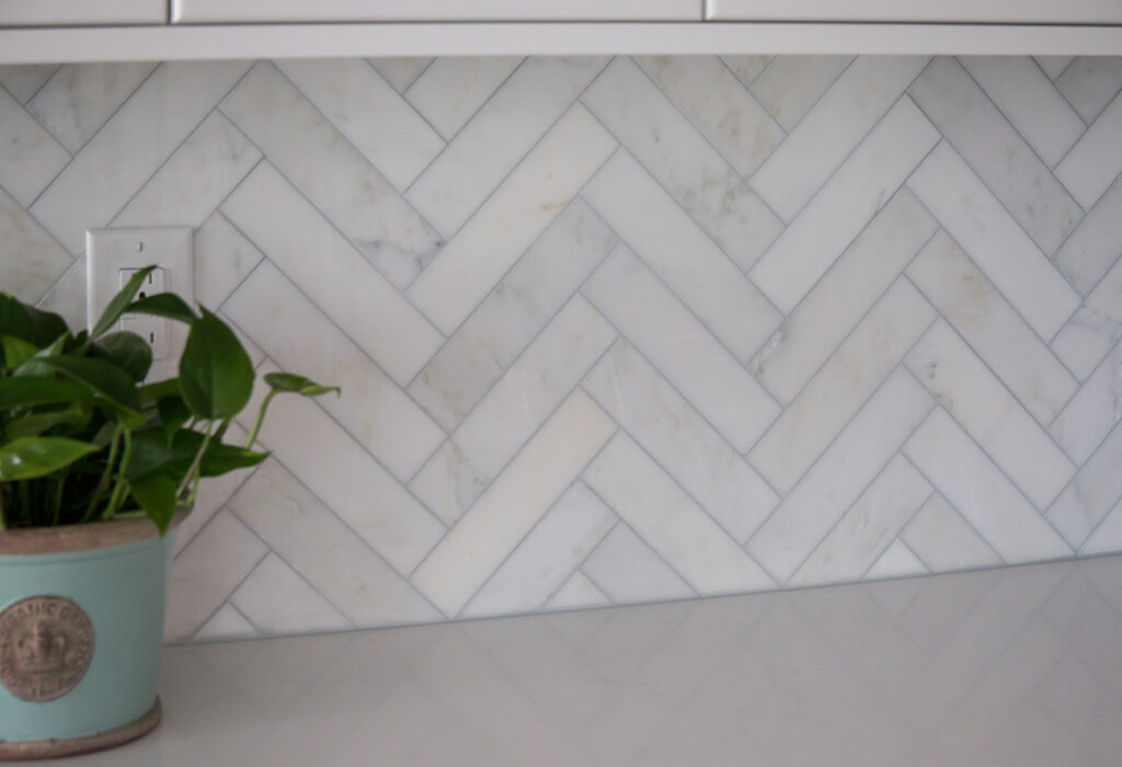 The kitchen backsplash is Akdo “Carrara Bella” Marble field tile, polished, 2 x 8 tile installed in a herringbone pattern. 