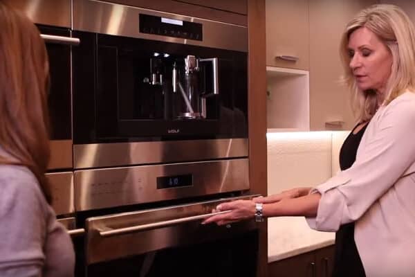 JM Kitchen & Bath Design employee shows customer how to use oven in showroom