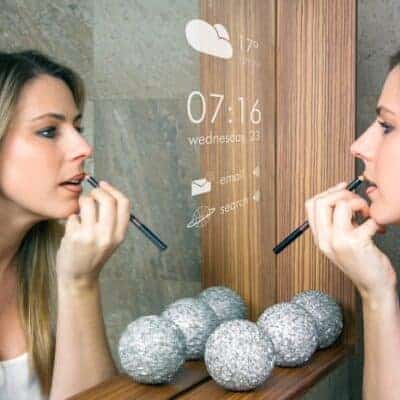 Smart mirror concept. Young woman applying lip liner in front of a smart mirror that gives information JM Kitchen & Bath Design